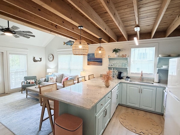 A spacious kitchen with a large island, light blue cabinets, and a ceiling fan.