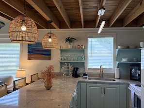 A kitchen with a central island, pendant lighting, and a view of the dining area.