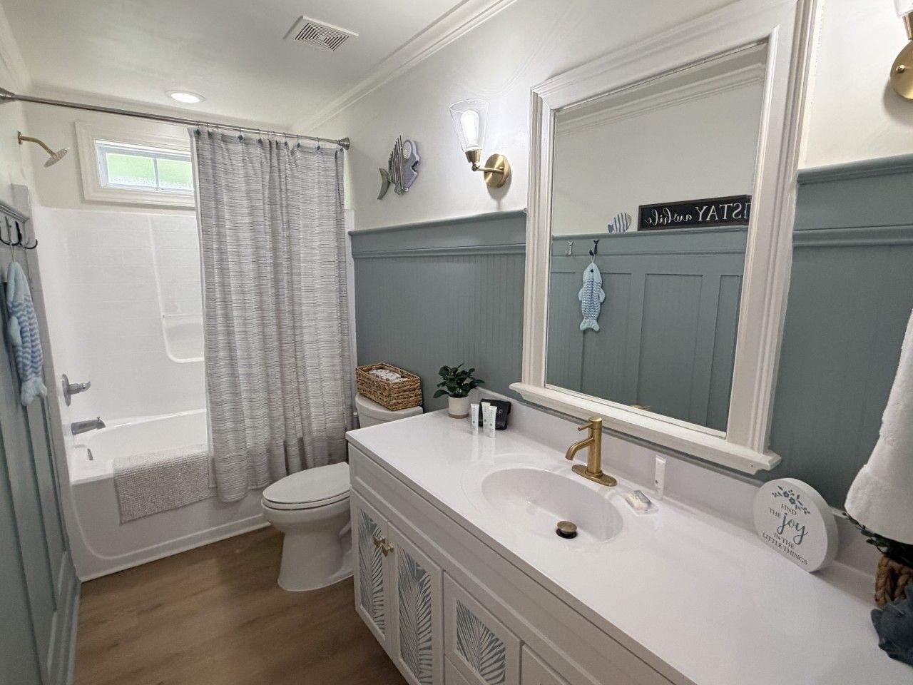 A bathroom with a bathtub, toilet, vanity with a sink, and a large mirror.