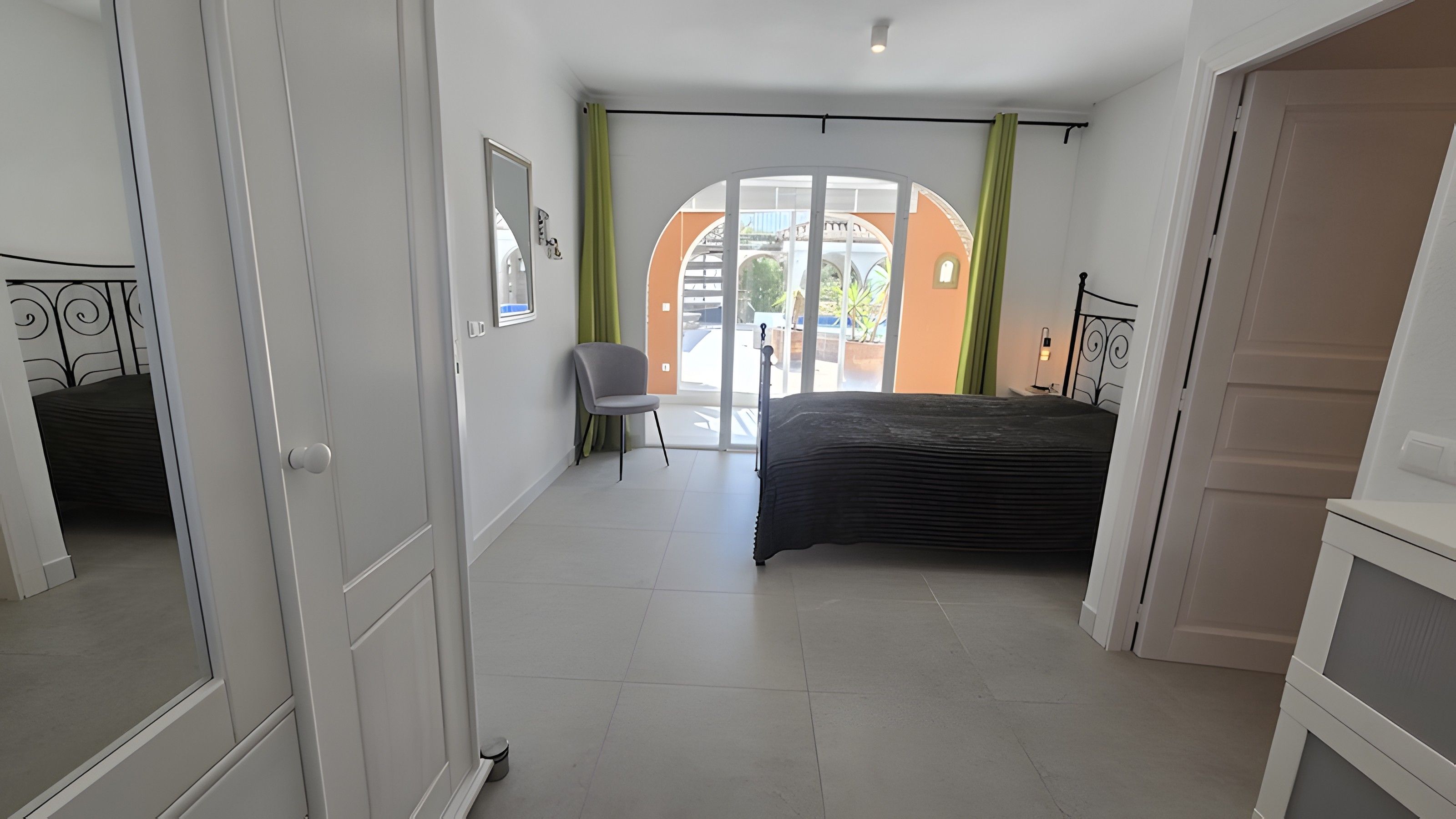 Une chambre à coucher avec un lit, une chaise, une fenêtre avec des rideaux et une porte.