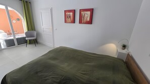 Une chambre à coucher avec un lit, une chaise, une porte et deux tableaux accrochés au mur.