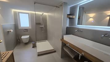 Une salle de bain moderne avec une douche à parois de verre, des toilettes et un meuble-lavabo avec un miroir.