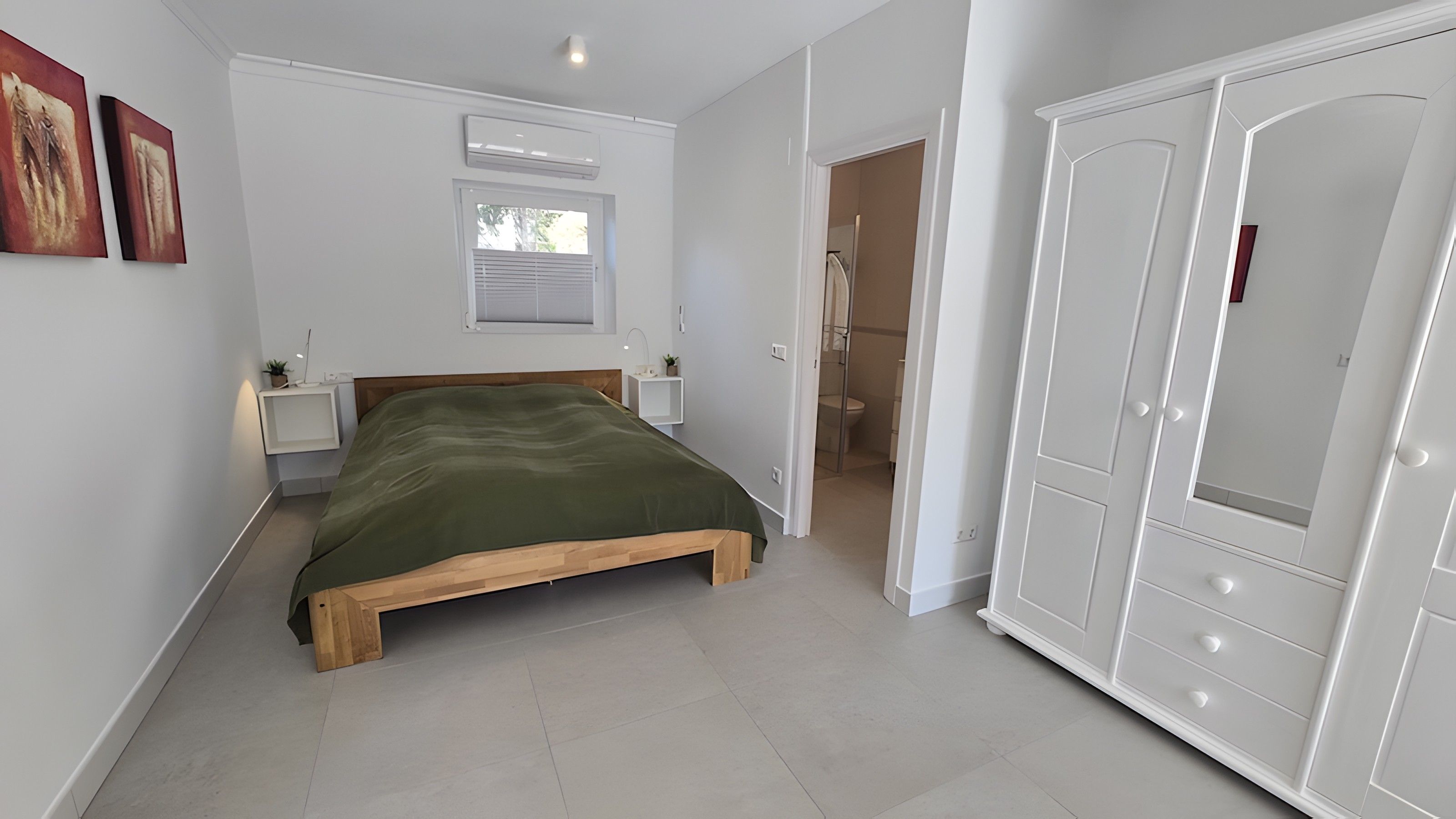 Ein Schlafzimmer mit einem hölzernen Bett, weißen Wänden und einem Kleiderschrank.