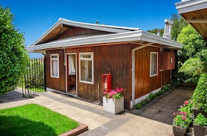 A small wooden cabin with a sloped roof, a front porch, and a mailbox.