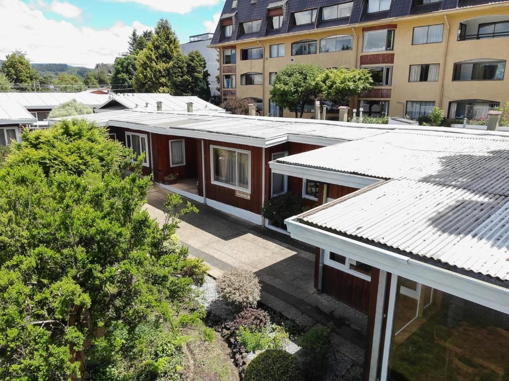 A residential building with a flat roof, multiple windows, and a garden area with trees.