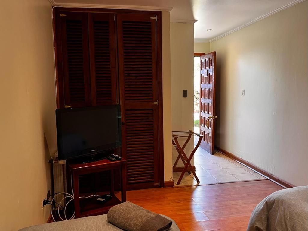 A room with a television on a wooden stand, a folding chair, and a door leading to another room.