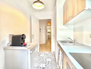 A compact kitchen with a coffee machine, a sink, and patterned flooring. - New Listing (Serris)