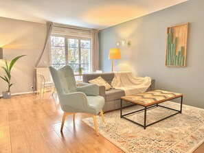 A living room with a sofa, armchair, coffee table, and a large window with curtains. - New Listing (Serris)