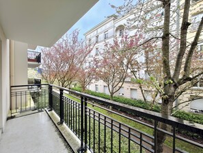 A balcony with a metal railing overlooking a residential area with trees and a building. - New Listing (Serris)