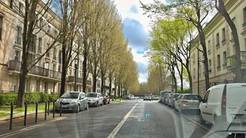 Een straat met geparkeerde auto's en bomen, met gebouwen aan beide zijden.