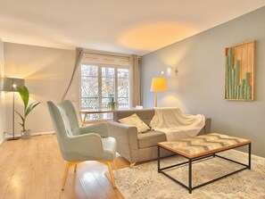 A living room with a sofa, armchair, coffee table, and a window with curtains. - New Listing (Serris)