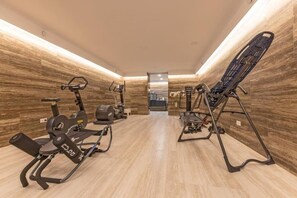 A gym with exercise equipment, a mirrored wall, and a wooden floor.