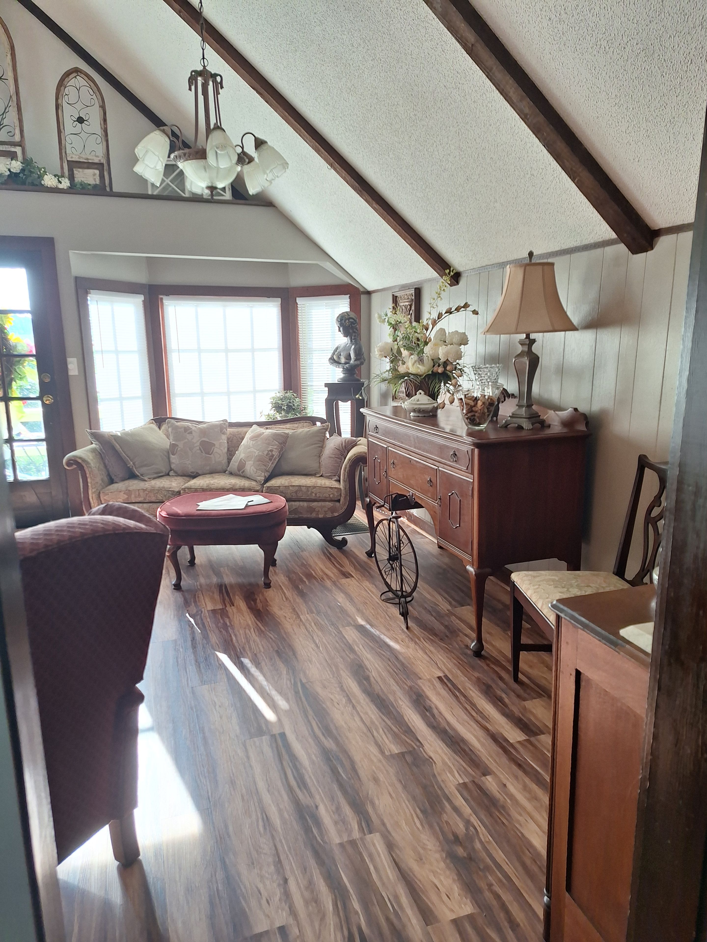 A cozy living room with a wooden floor, a sofa, a coffee table, and a lamp.