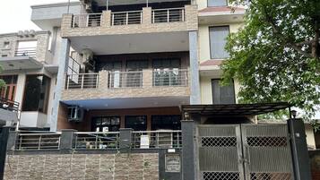 Un edificio residencial de varios pisos con entrada protegida por una reja, un balcón y un letrero que indica el nombre de la propiedad.