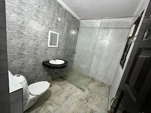 Une salle de bain avec des toilettes, un lavabo et une douche.