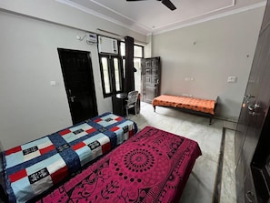 Une chambre avec deux lits, un bureau, une chaise et une armoire.
