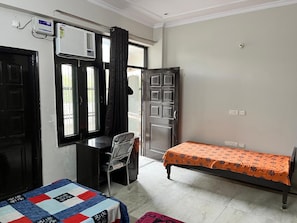 Une chambre comprenant un lit, un bureau, une chaise et un appareil de climatisation.
