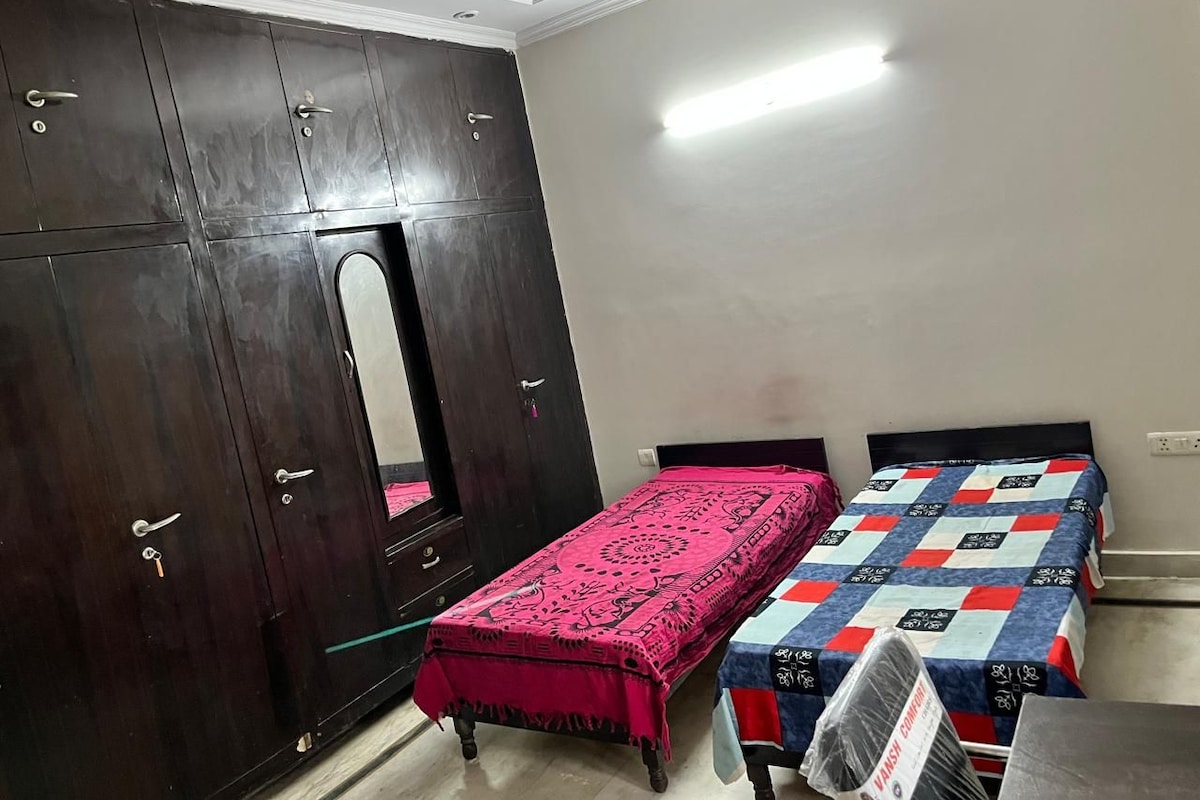 Una habitación con armario, cama con colcha estampada y espejo.