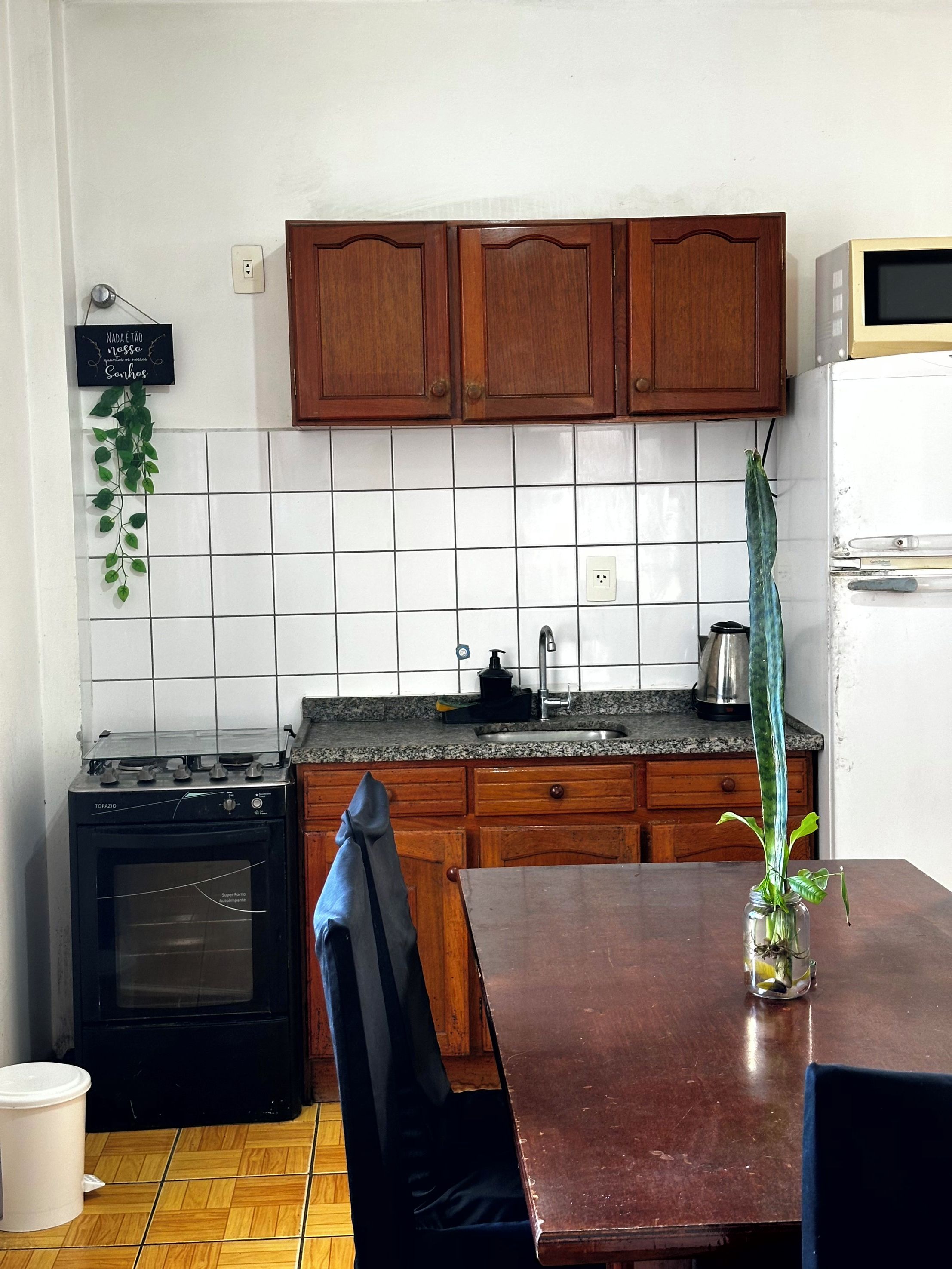 A kitchen with wooden cabinets, a stove, a sink, and a refrigerator.