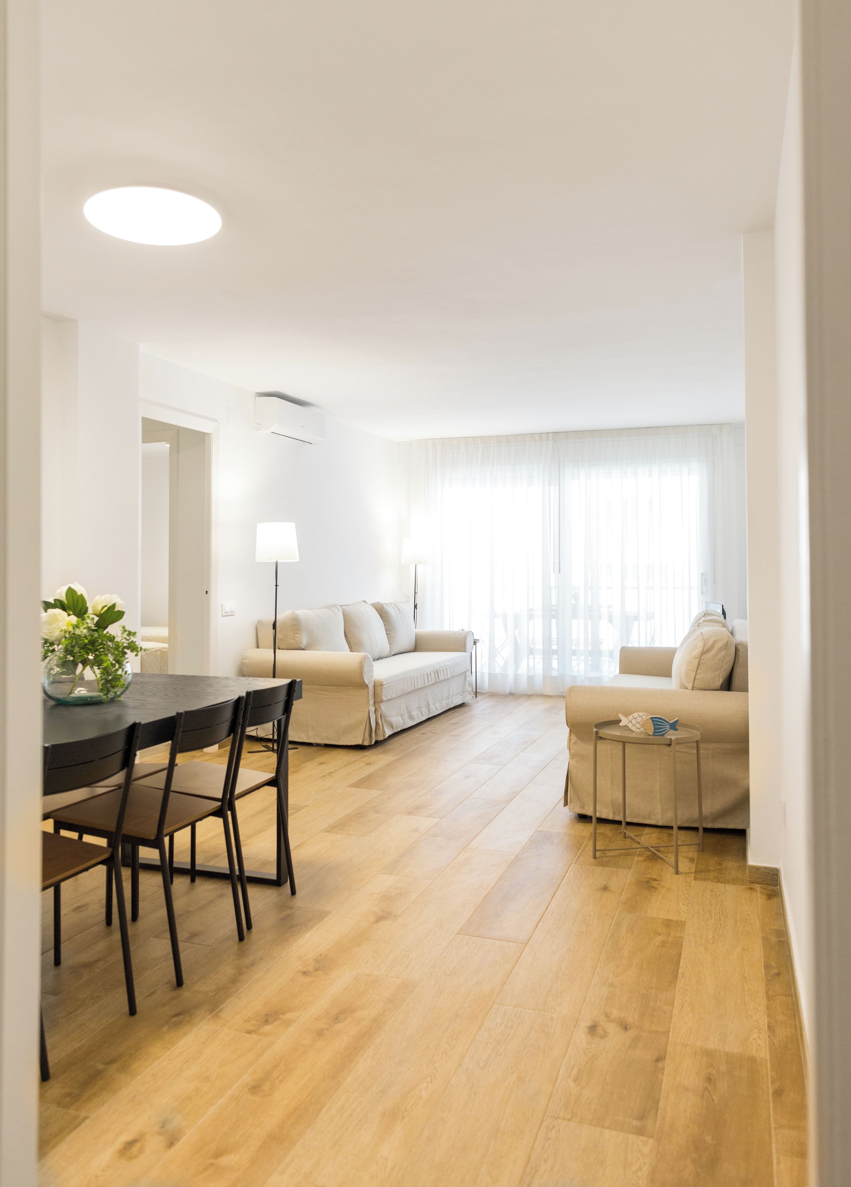 Een moderne woonkamer met een bank, een eettafel met stoelen en een bijzettafeltje met een decoratief object.