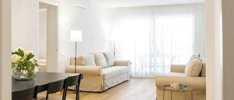 Un salon moderne comprenant un canapé, une table à manger avec des chaises et une petite table d’appoint agrémentée d’un objet décoratif.