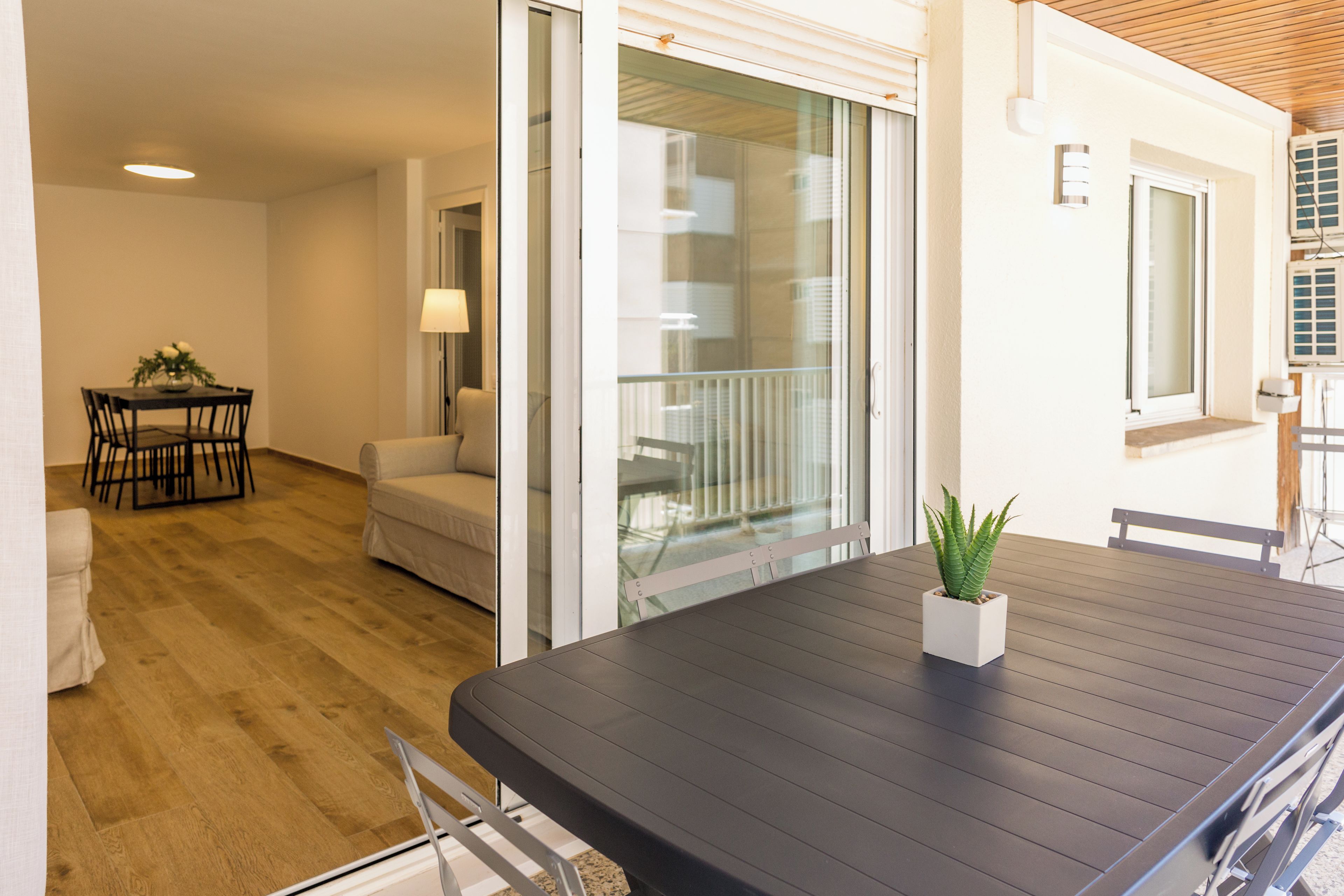 Un intérieur moderne avec une table en bois foncé, un canapé blanc et une petite plante en pot.