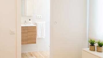 Een moderne badkamer met een houten wastafelmeubel, een spiegel en een handdoek aan de muur.