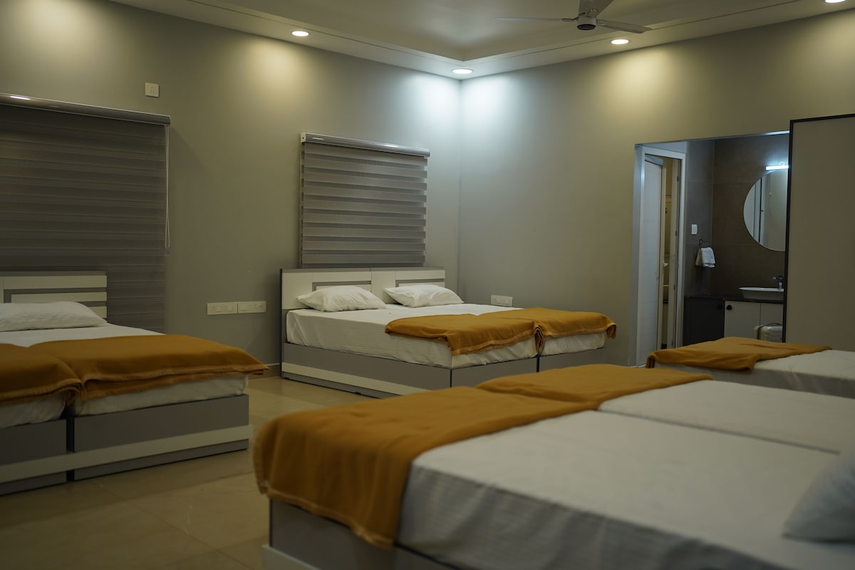 A hotel room with three beds, a large mirror, and a ceiling fan.