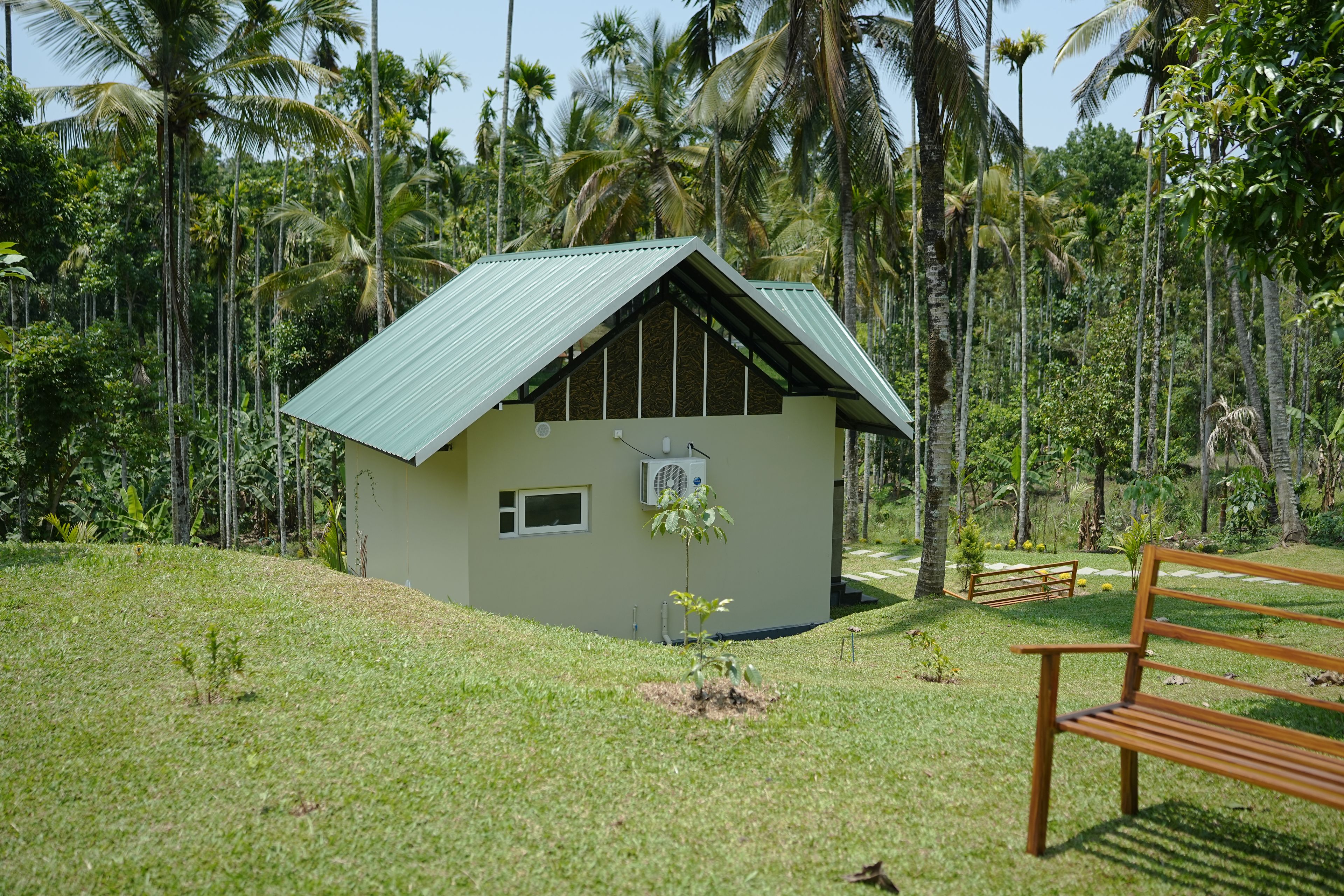Un petit bâtiment d’un seul étage, doté d’un toit en pente et entouré d’un paysage tropical luxuriant.