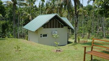 Un petit bâtiment d’un seul étage, doté d’un toit en pente et entouré d’un paysage tropical luxuriant.