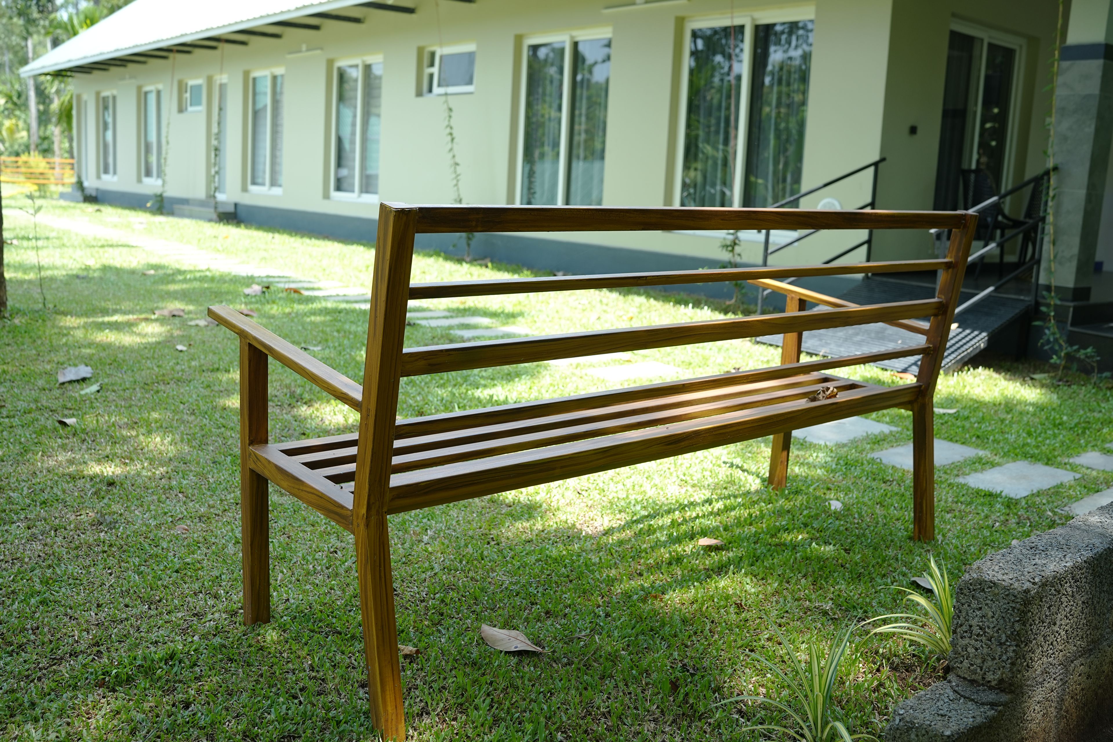 A wooden bench in a grassy area with a building in the background.