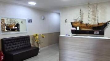 A reception area with a reception desk, a black sofa, and a ship model on the wall.
