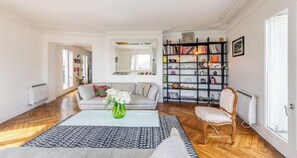 A living room with a sofa, a coffee table, a bookshelf, and a chair. - YOUR PARISIAN HOME AWAY FROM HOME SAINT LAZARE - RUE CLAPEYRON (Paris)