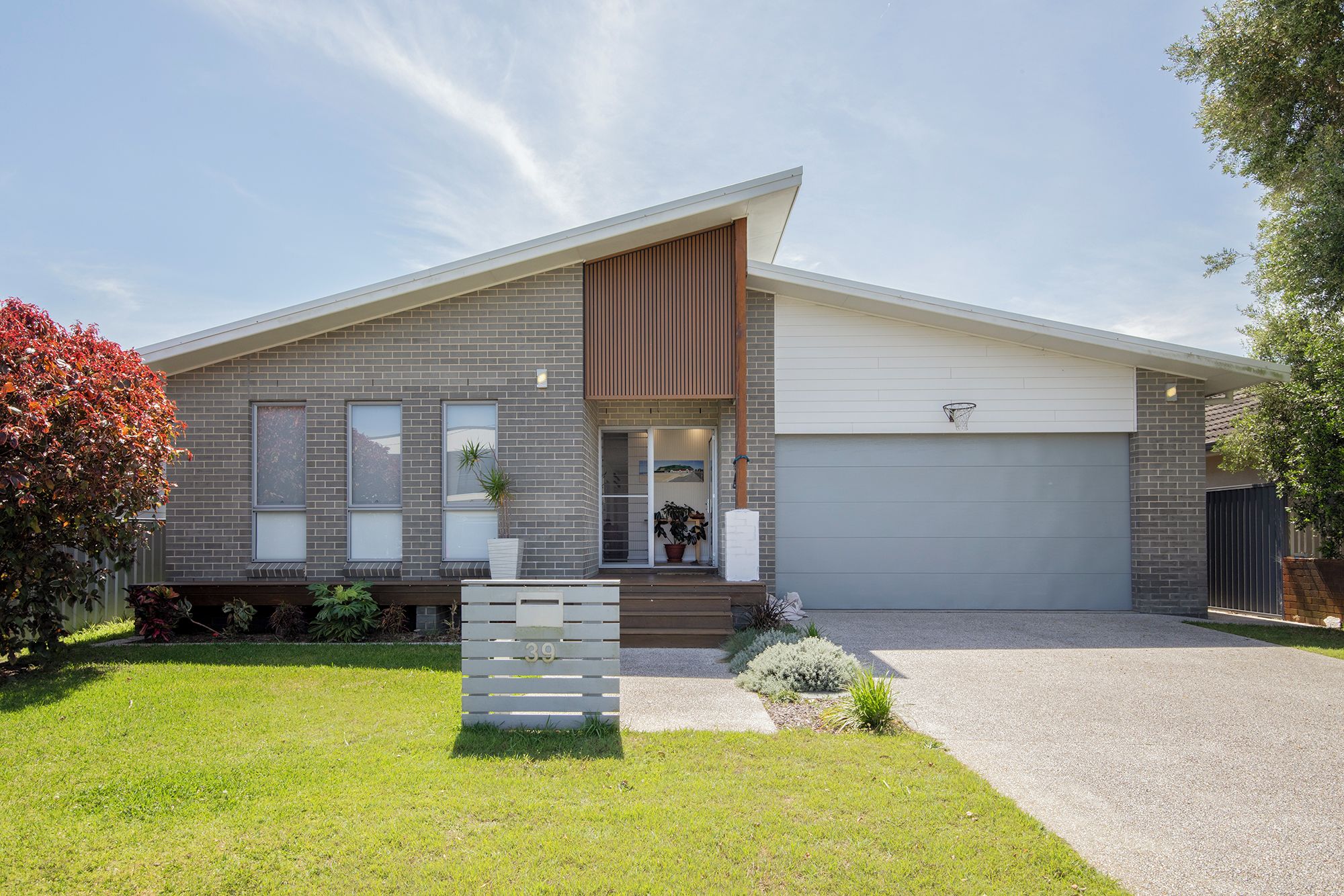 A modern two-story house with a garage, a front porch, and a well-maintained lawn.