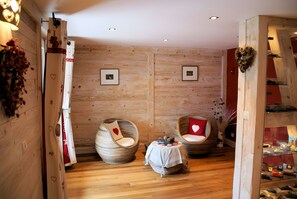 Una habitación con paredes de madera, dos sillones redondos con cojines con forma de corazón, una mesita y cuadros enmarcados en la pared.