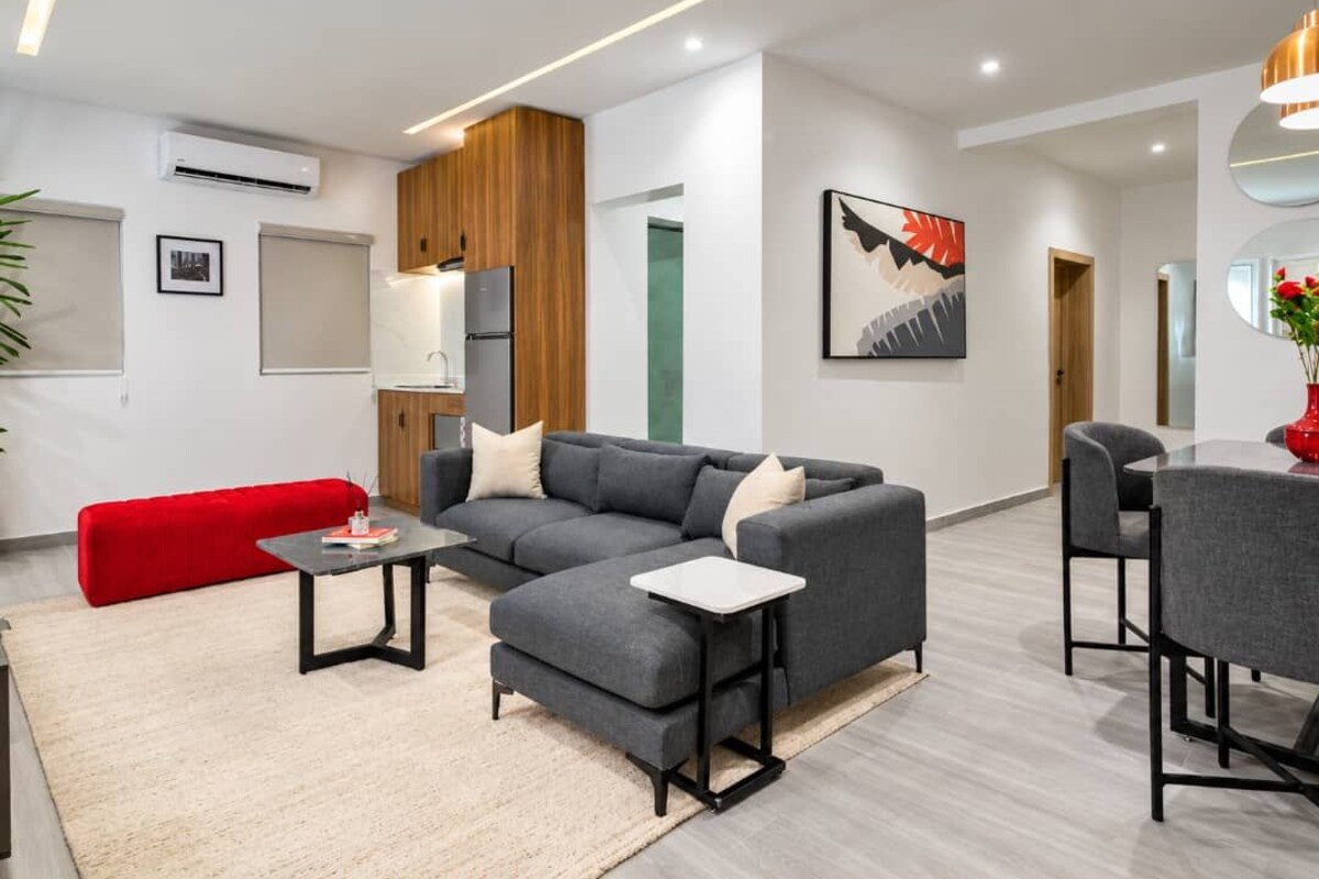 Una sala de estar moderna con un sofá modular, una mesita de centro y un comedor con sillas.