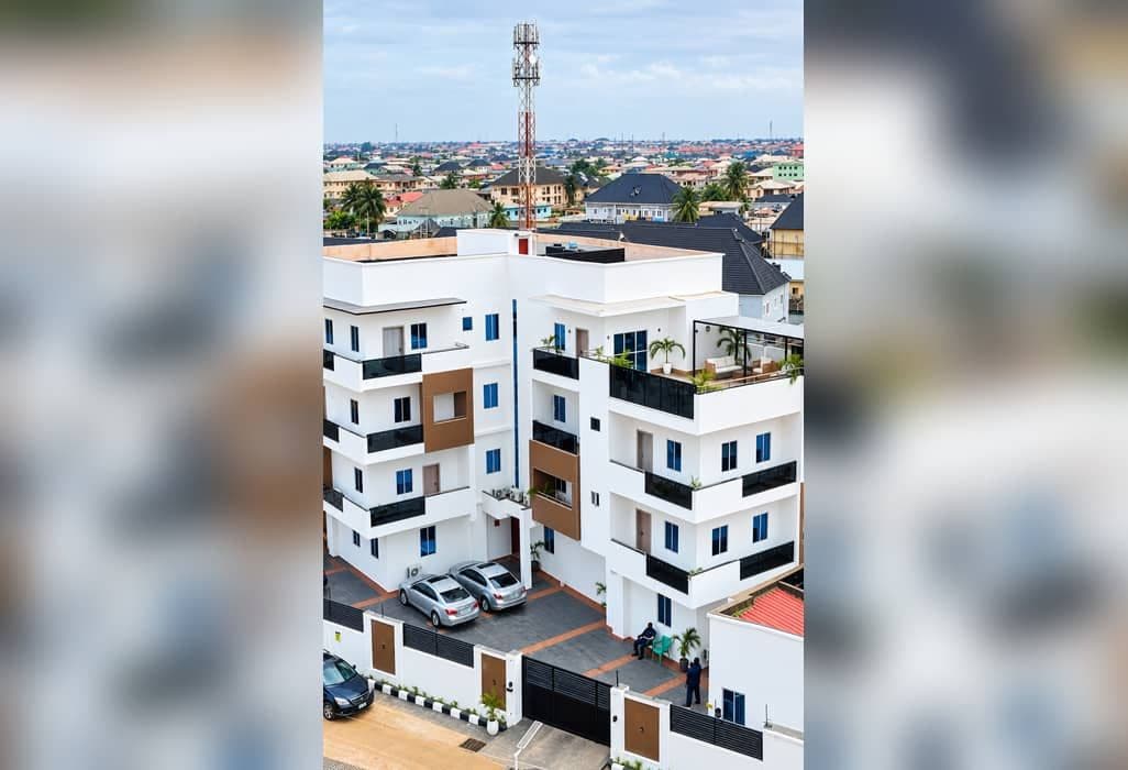 Un edificio residencial de varios pisos con balcones, un estacionamiento y vistas despejadas del barrio circundante.