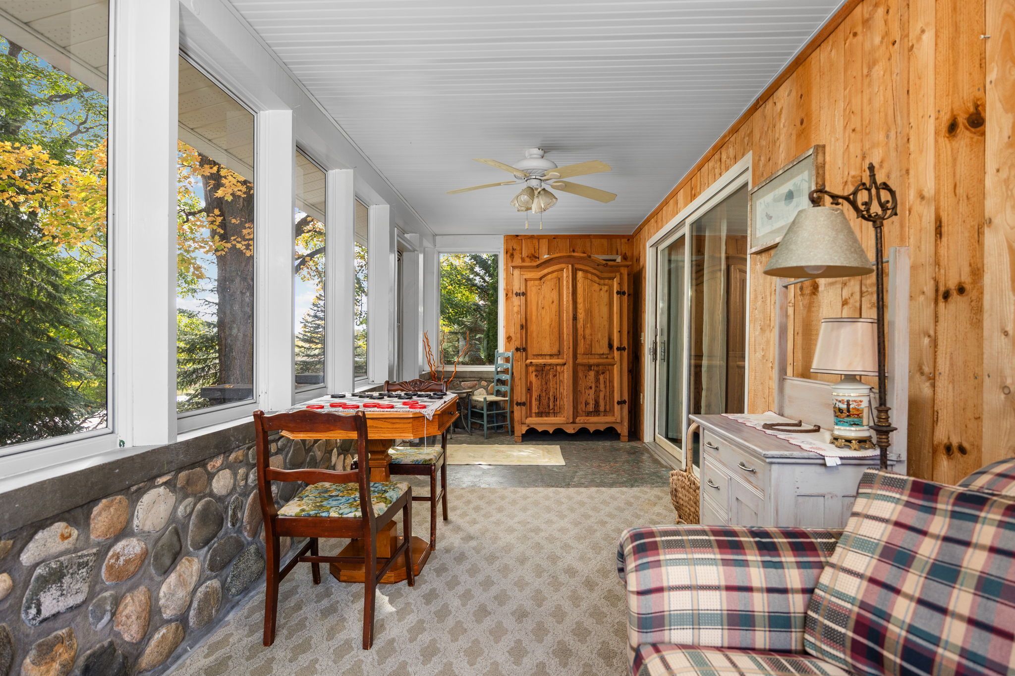 A cozy interior with a dining area, wooden walls, and a view of trees.