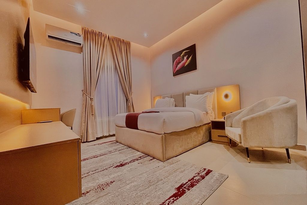 Una habitación de hotel moderna con una cama grande, un escritorio, una silla y una mesita de noche.