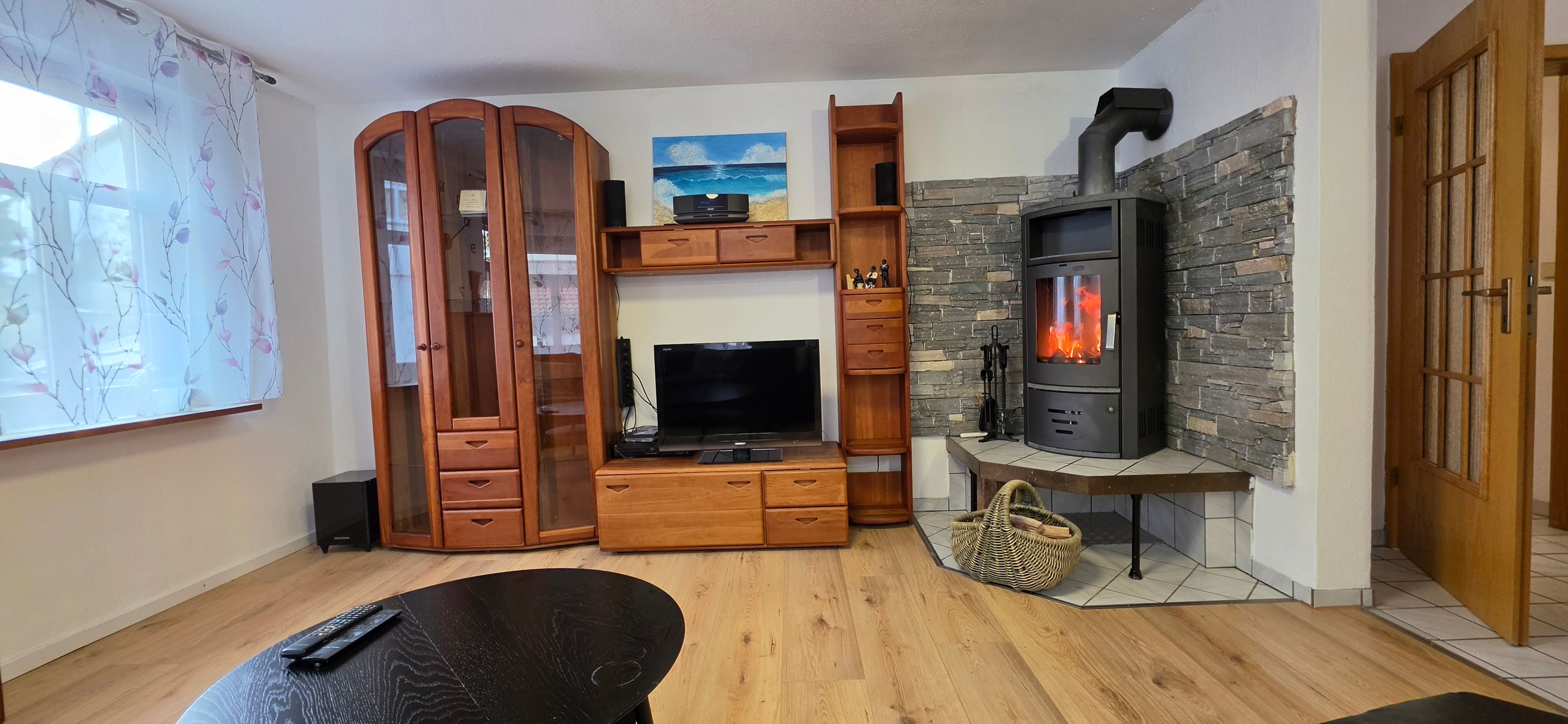 Un salon équipé d’un téléviseur, d’un meuble de rangement en bois, d’une cheminée en pierre et d’une porte.