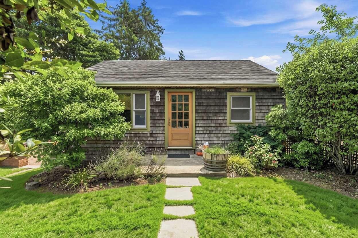 A single-story house with a front door, a small porch, and a stone pathway leading to the entrance.