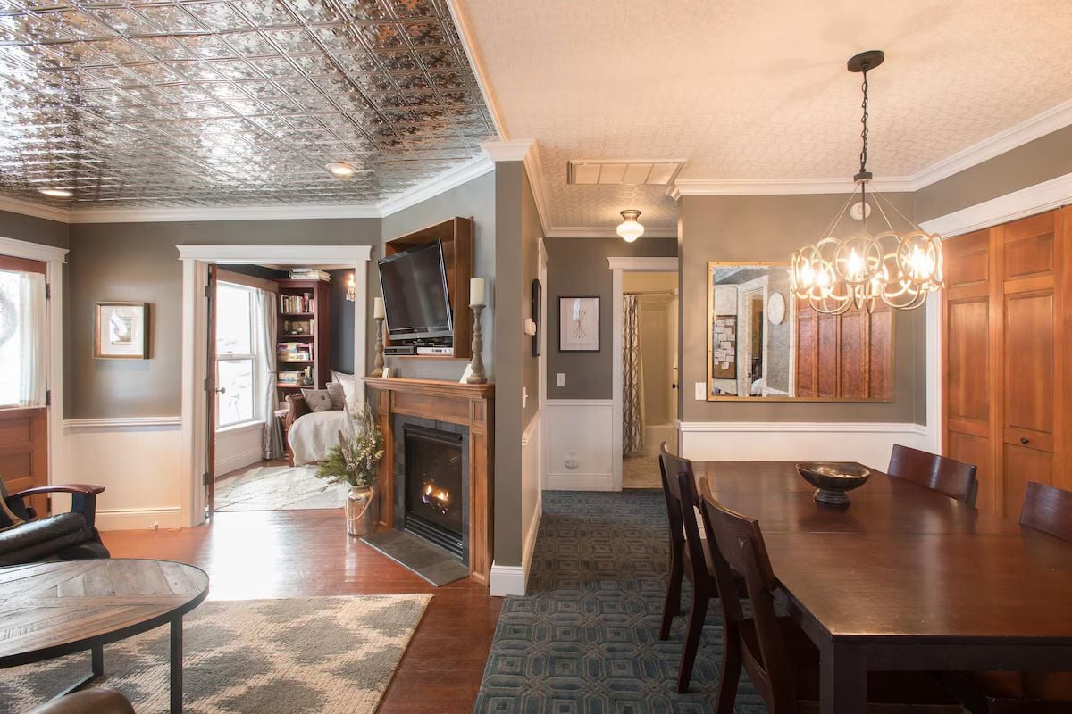 A dining area with a fireplace, wooden furniture, and a chandelier.