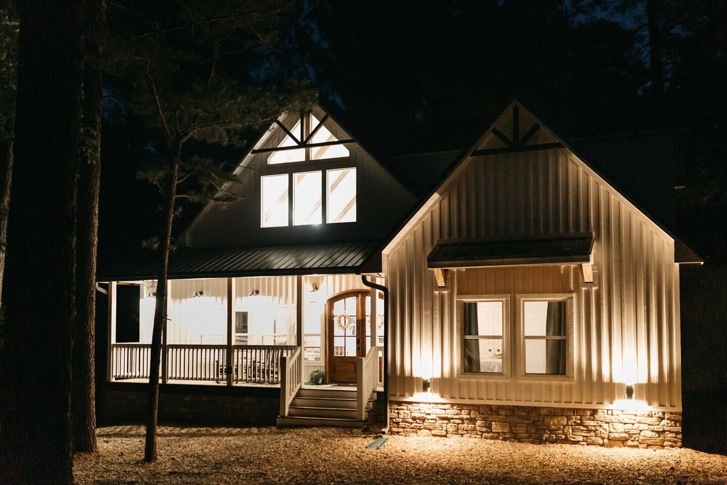 Eine zweistöckige Holzhütte mit Veranda und Steinunterbau.