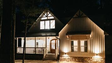 Eine zweistöckige Holzhütte mit Veranda und Steinunterbau.