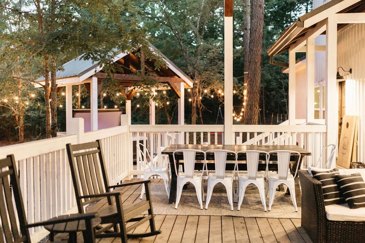Eine Terrasse im Freien mit einem Holztisch und -stühlen, umgeben von einem weißen Geländer.