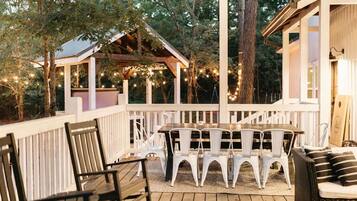 Eine Terrasse im Freien mit einem Holztisch und -stühlen, umgeben von einem weißen Geländer.