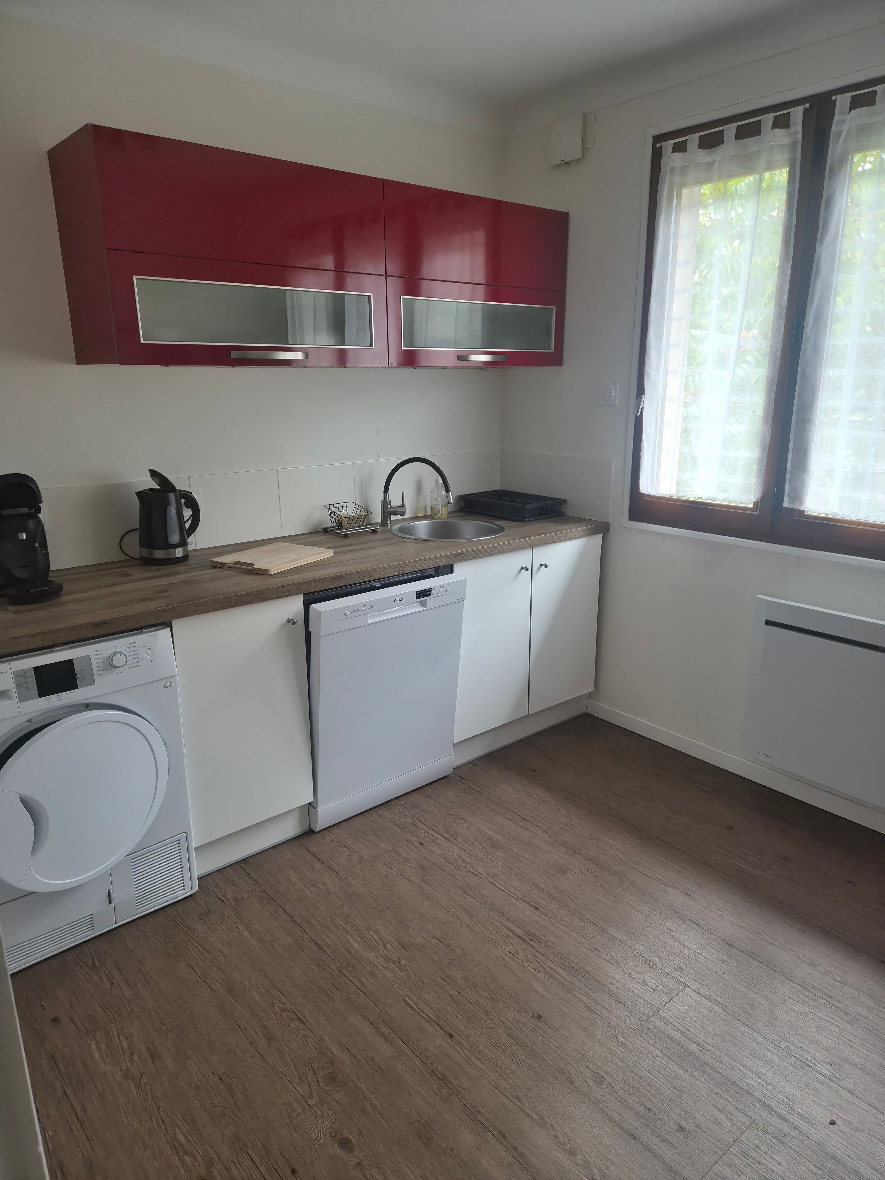 Een kleine keuken met een wasmachine, een koffiezetapparaat en een gootsteen.