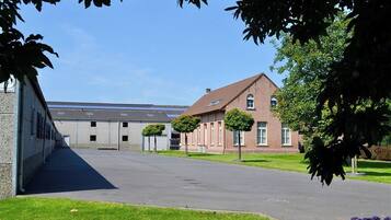A building with a paved driveway, a brick building, and a row of windows.
