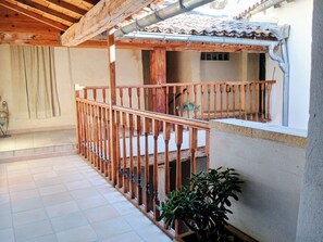A wooden balcony with a railing, a tiled floor, and a potted plant. - New Listing (L'Isle-sur-la-Sorgue)