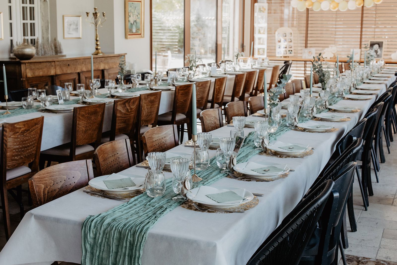A long dining table set with chairs, glassware, and plates, indicating a formal dining area.